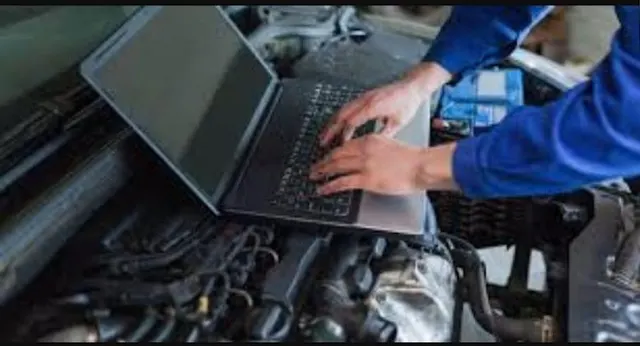 A diagnostic laptop plugged in over an open engine bay.